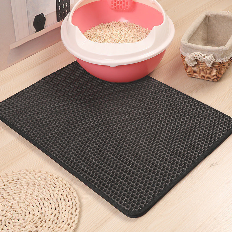 Black textured double-layer cat litter trapping mat in front of a pink litter box