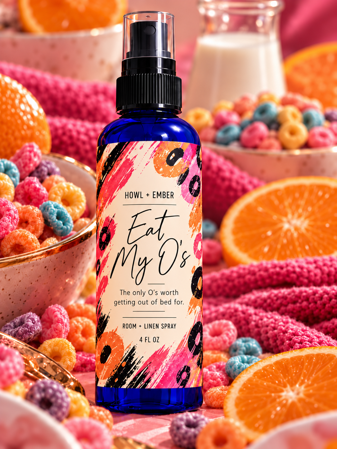 Howl + Ember Eat My O's 4 oz room and linen spray on cobalt blue fine-mist bottle with orange, coral, pink and black abstract label, and The only O's worth getting out of bed for tagline, styled with cereal and citrus
